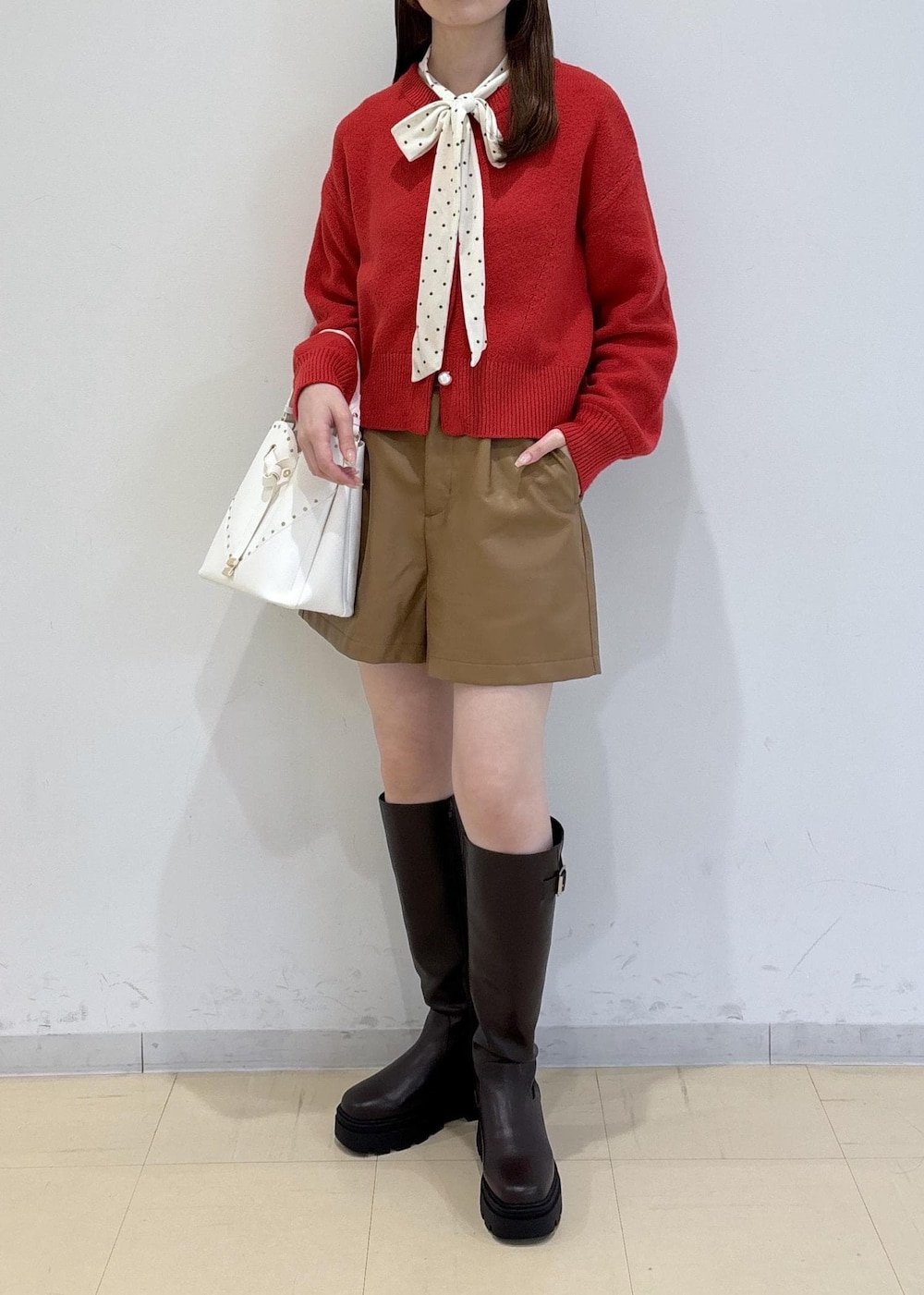 ブラウン系のブーツ、レッド系のカーディガン/ボレロ、ホワイト系のTシャツ/カットソーを着用したレディースの冬コーディネートの3枚目の写真