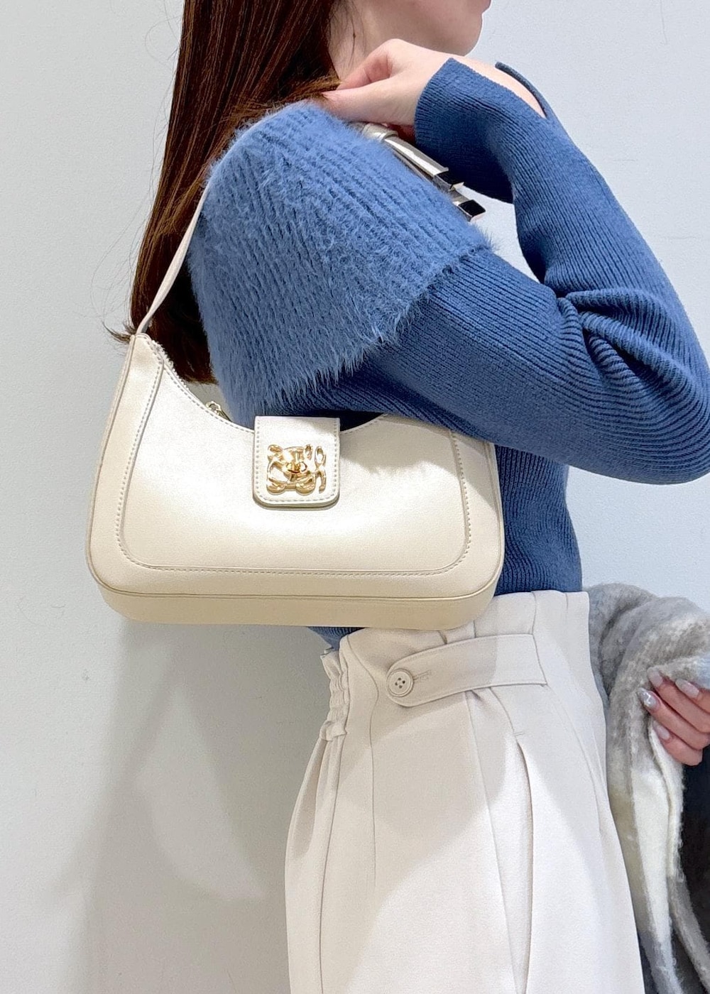 ホワイト系のショルダーバッグ、ブラック系のブーツ、ブルー系のニット/セーターを着用したレディースの秋コーディネートの9枚目の写真