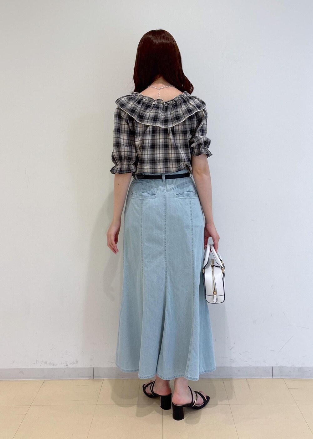 ブラック系のサンダル、ブルー系のデニムスカート、ホワイト系のショルダーバッグを着用したレディースの夏コーディネートの4枚目の写真