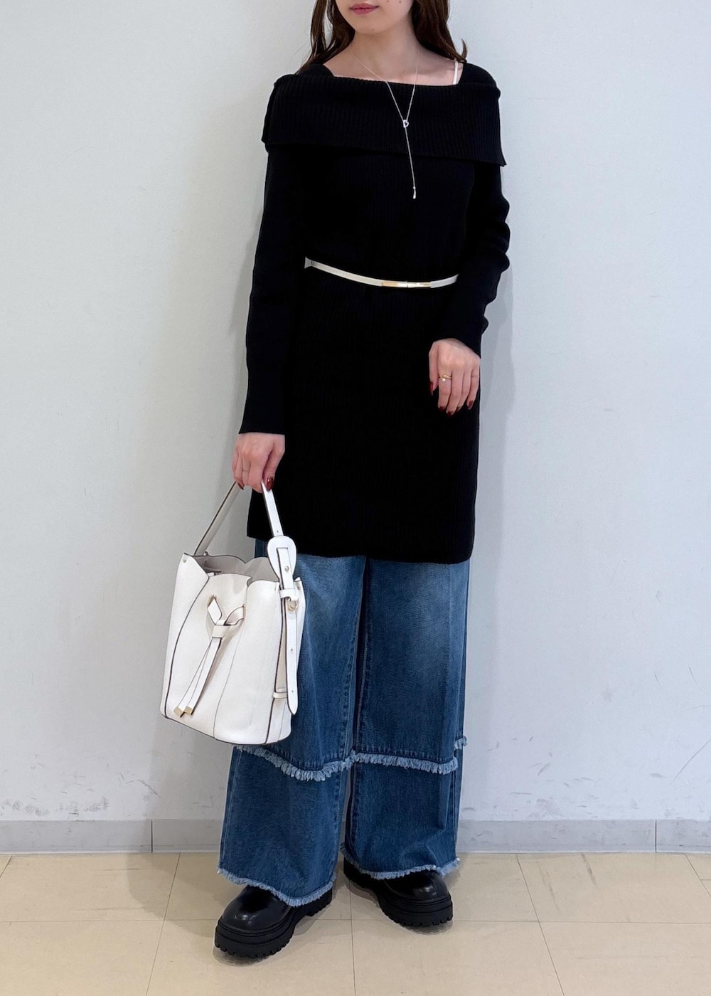 ブルー系のデニムパンツ、ブラック系のブーツ、ホワイト系のショルダーバッグを着用したレディースの秋コーディネートの2枚目の写真