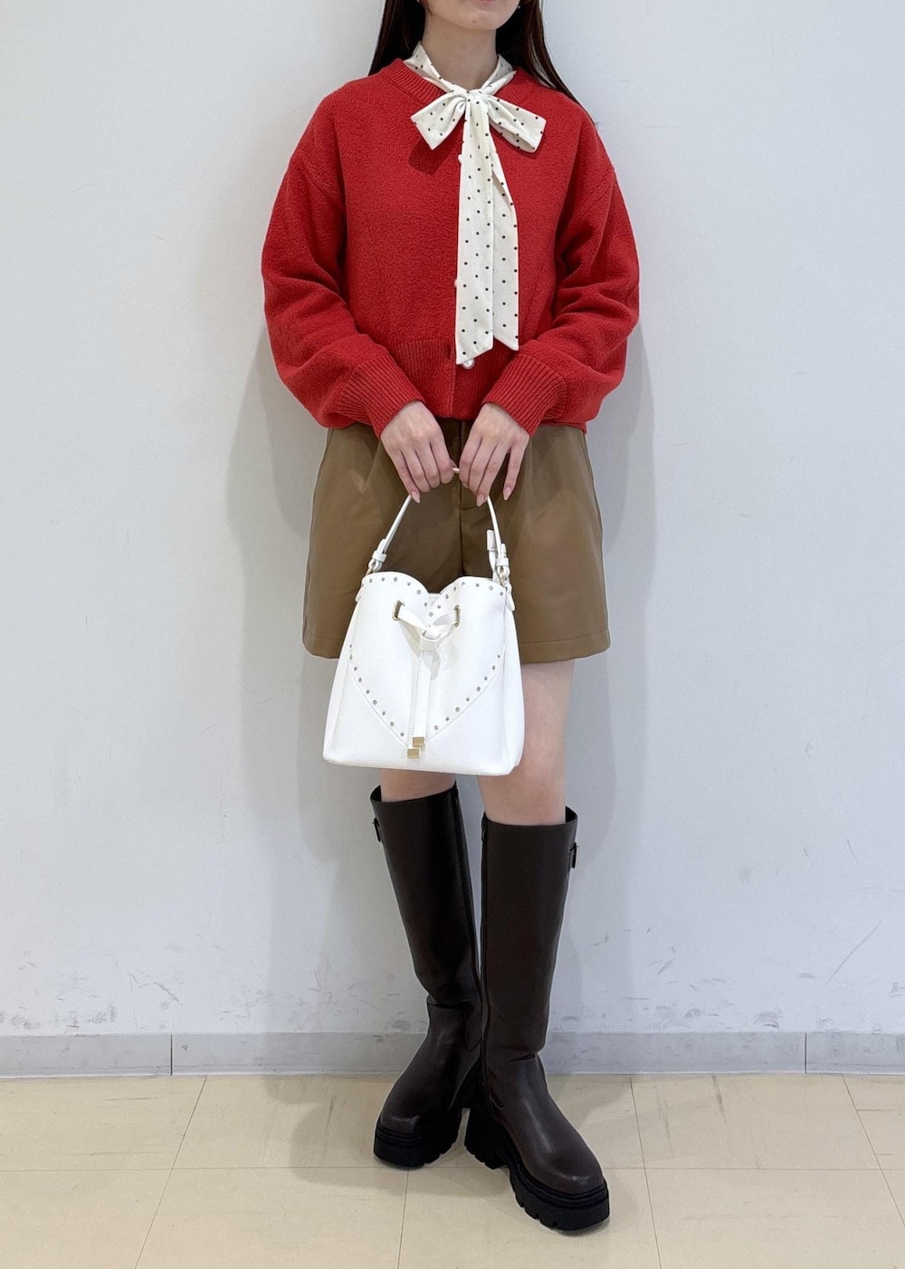 ブラウン系のブーツ、レッド系のカーディガン/ボレロ、ホワイト系のTシャツ/カットソーを着用したレディースの冬コーディネートの2枚目の写真