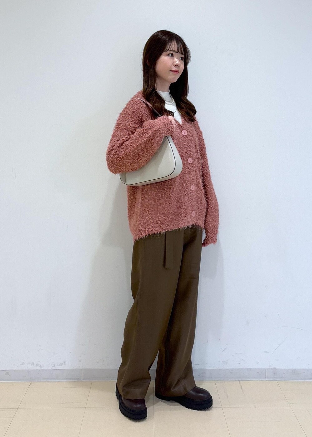 ブラウン系のブーツ、ピンク系のカーディガン/ボレロ、ホワイト系のニット/セーターを着用したレディースの冬コーディネートの2枚目の写真