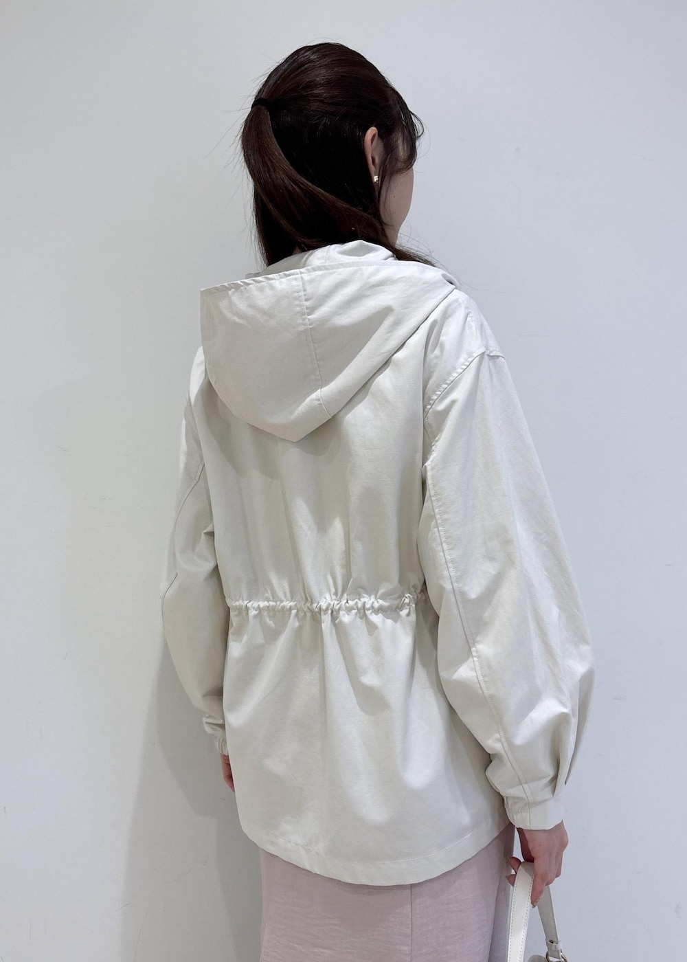 ホワイト系のショルダーバッグ、ブラック系のパンプス、ホワイト系のナイロンジャケットを着用したレディースの春コーディネートの7枚目の写真