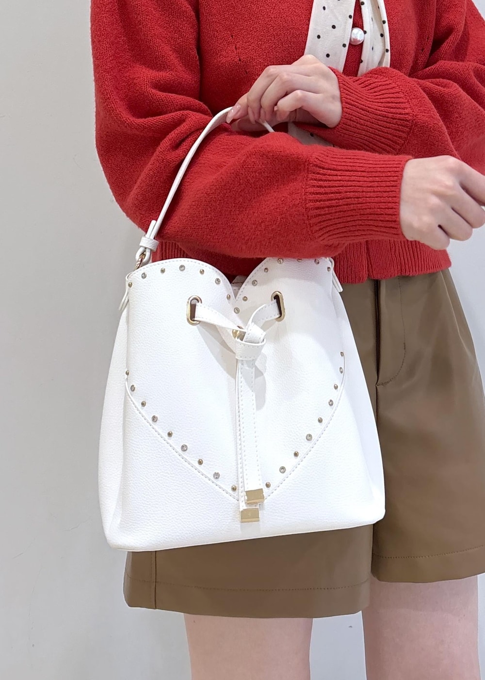 ブラウン系のブーツ、レッド系のカーディガン/ボレロ、ホワイト系のTシャツ/カットソーを着用したレディースの冬コーディネートの10枚目の写真