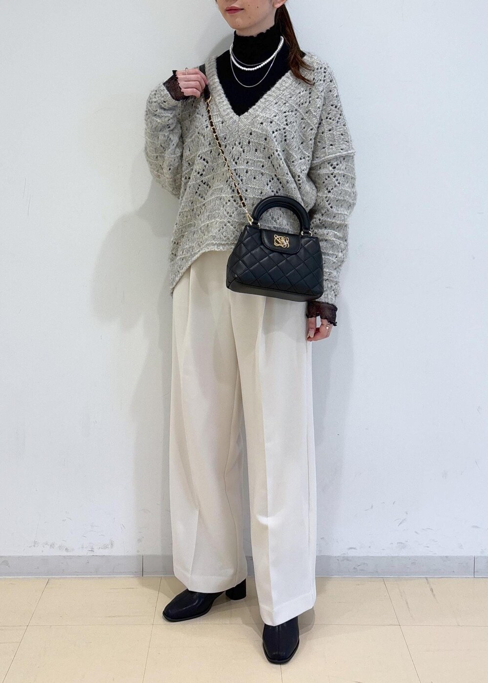 ブラック系のブーツ、ブラック系のTシャツ/カットソー、ベージュ系のニット/セーターを着用したレディースの冬コーディネートの5枚目の写真