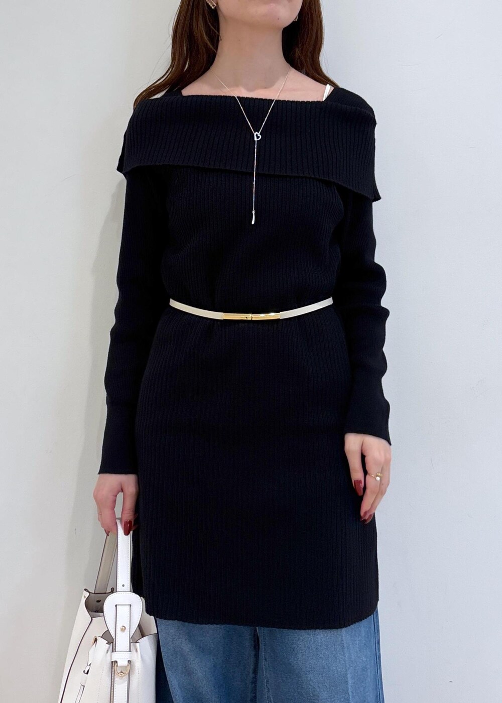 ブルー系のデニムパンツ、ブラック系のブーツ、ホワイト系のショルダーバッグを着用したレディースの秋コーディネートの6枚目の写真