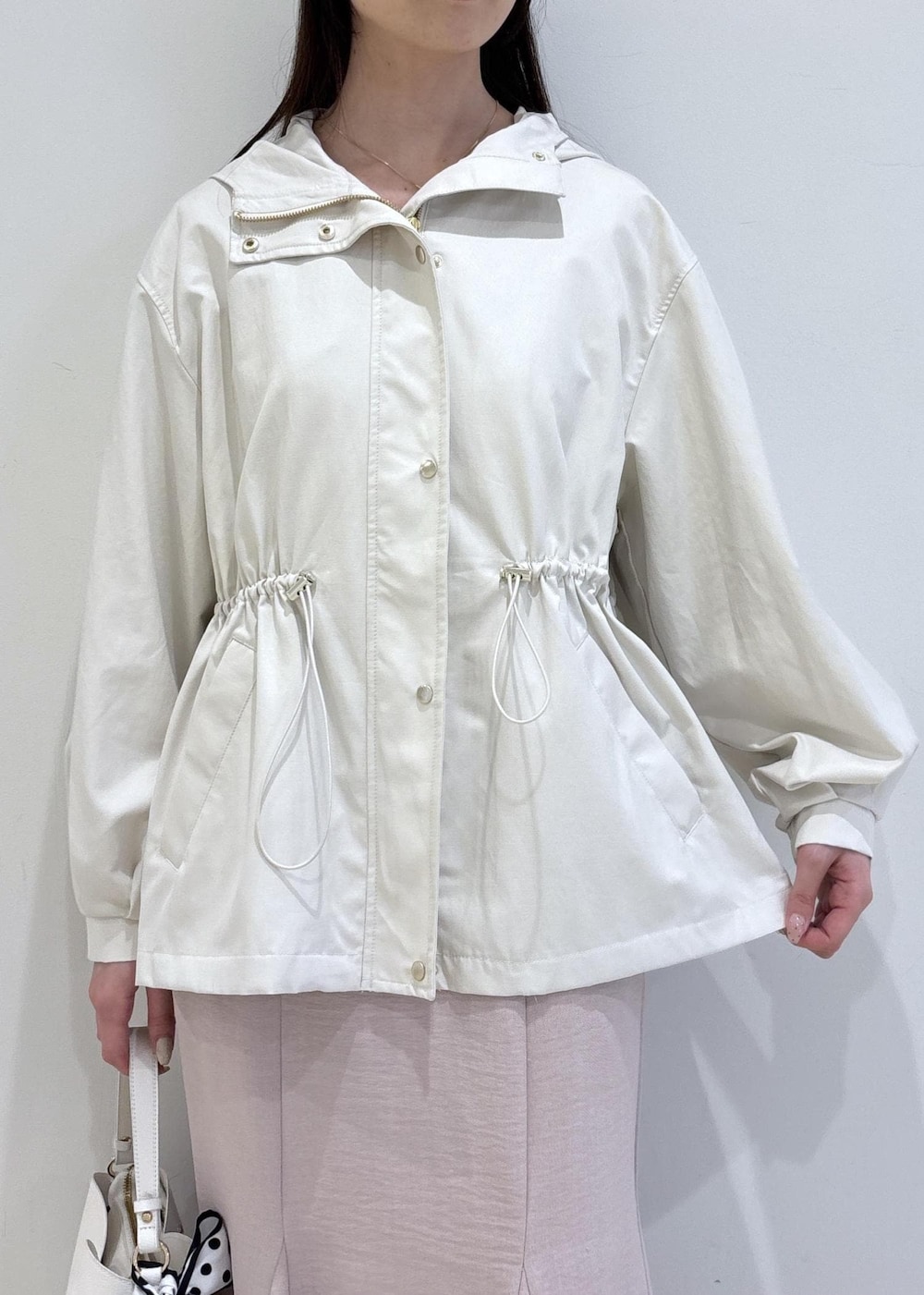 ホワイト系のショルダーバッグ、ブラック系のパンプス、ホワイト系のナイロンジャケットを着用したレディースの春コーディネートの6枚目の写真