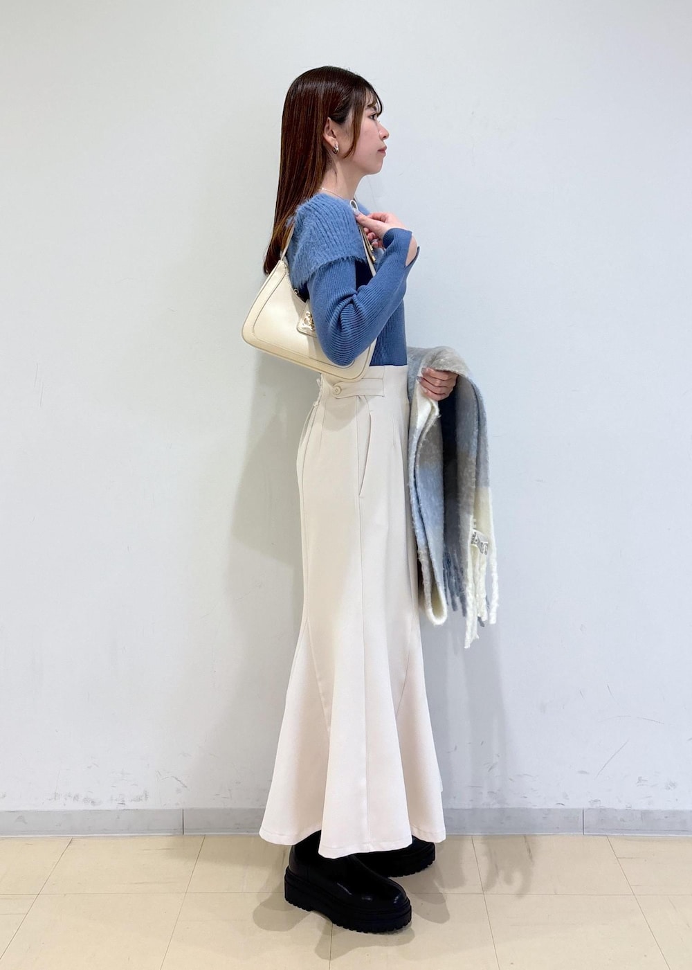 ホワイト系のショルダーバッグ、ブラック系のブーツ、ブルー系のニット/セーターを着用したレディースの秋コーディネートの3枚目の写真
