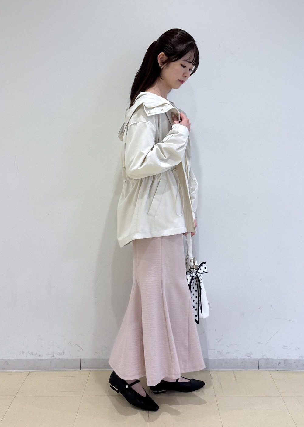 ホワイト系のショルダーバッグ、ブラック系のパンプス、ホワイト系のナイロンジャケットを着用したレディースの春コーディネートの2枚目の写真