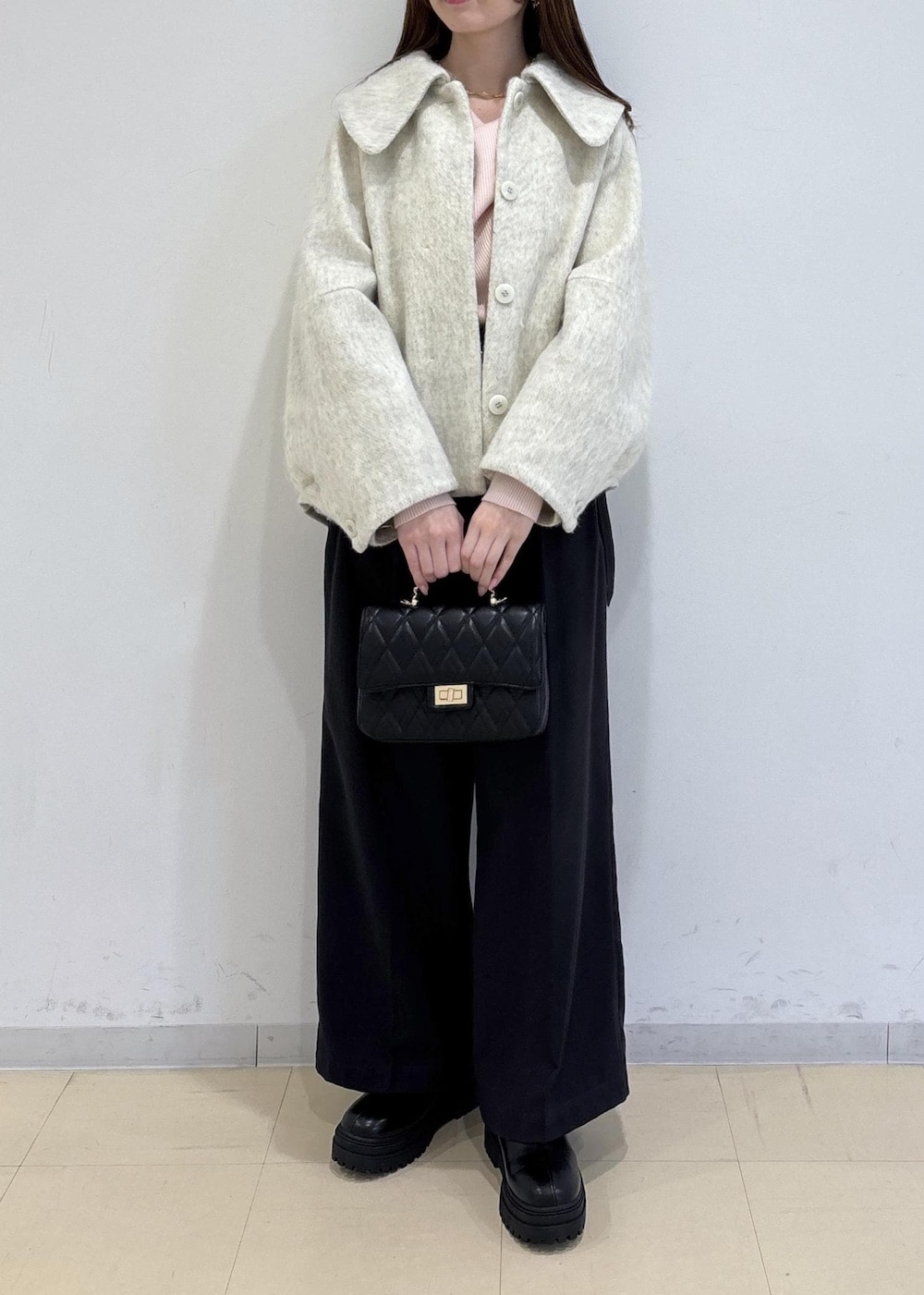 ブラック系のブーツ、ホワイト系のブルゾン、ピンク系のニット/セーターを着用したレディースの冬コーディネートの2枚目の写真