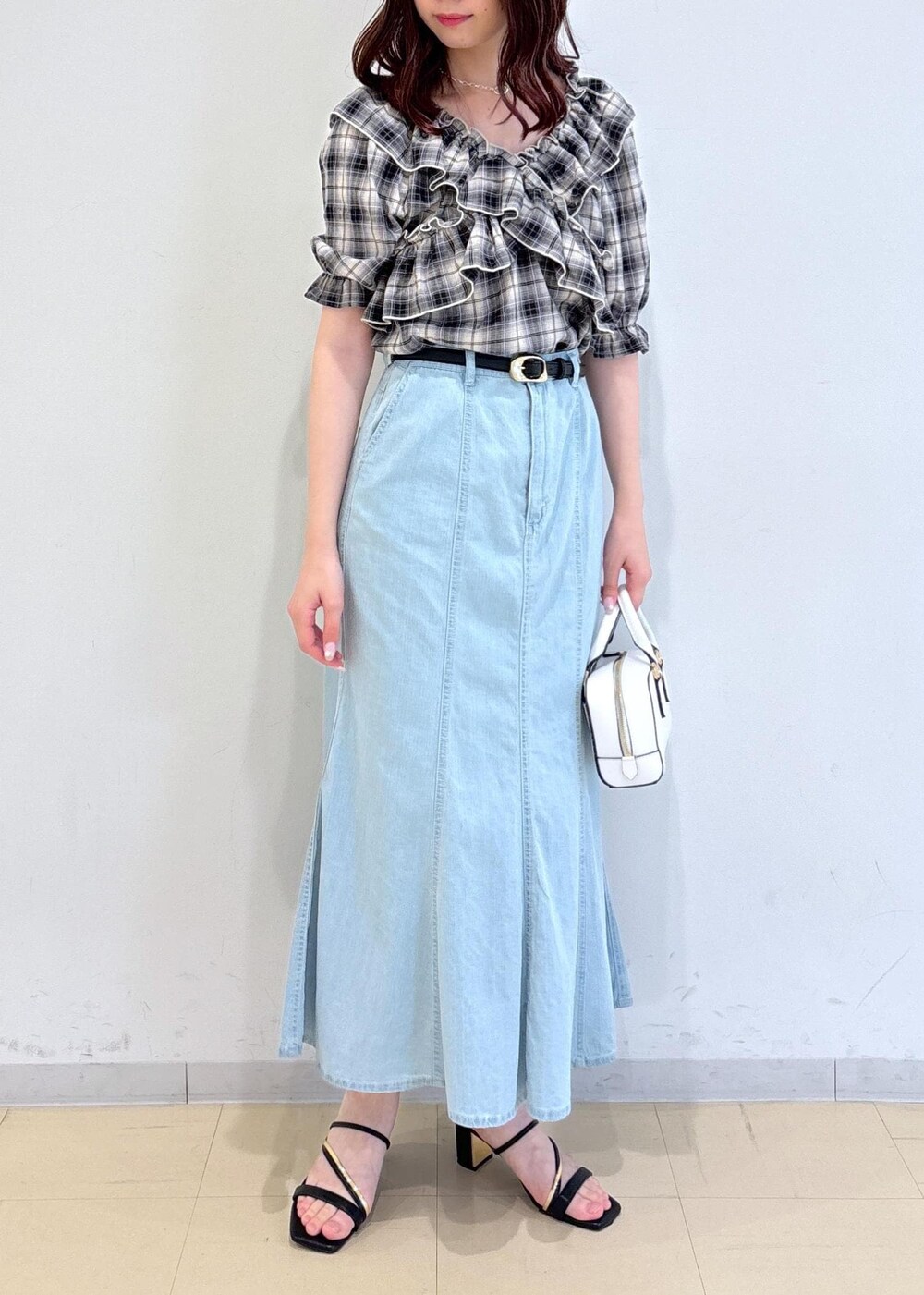 ブラック系のサンダル、ブルー系のデニムスカート、ホワイト系のショルダーバッグを着用したレディースの夏コーディネートの2枚目の写真