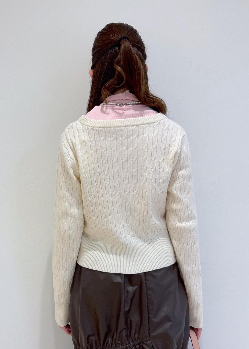 ピンク系のショルダーバッグ、ホワイト系のブーツ、ブラウン系のスカートを着用したレディースの冬コーディネートの8枚目の写真