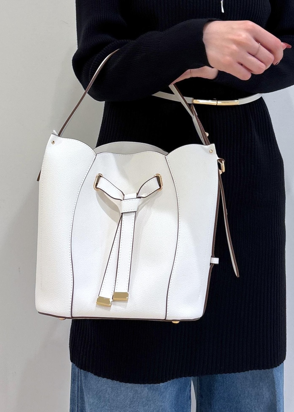 ブルー系のデニムパンツ、ブラック系のブーツ、ホワイト系のショルダーバッグを着用したレディースの秋コーディネートの10枚目の写真