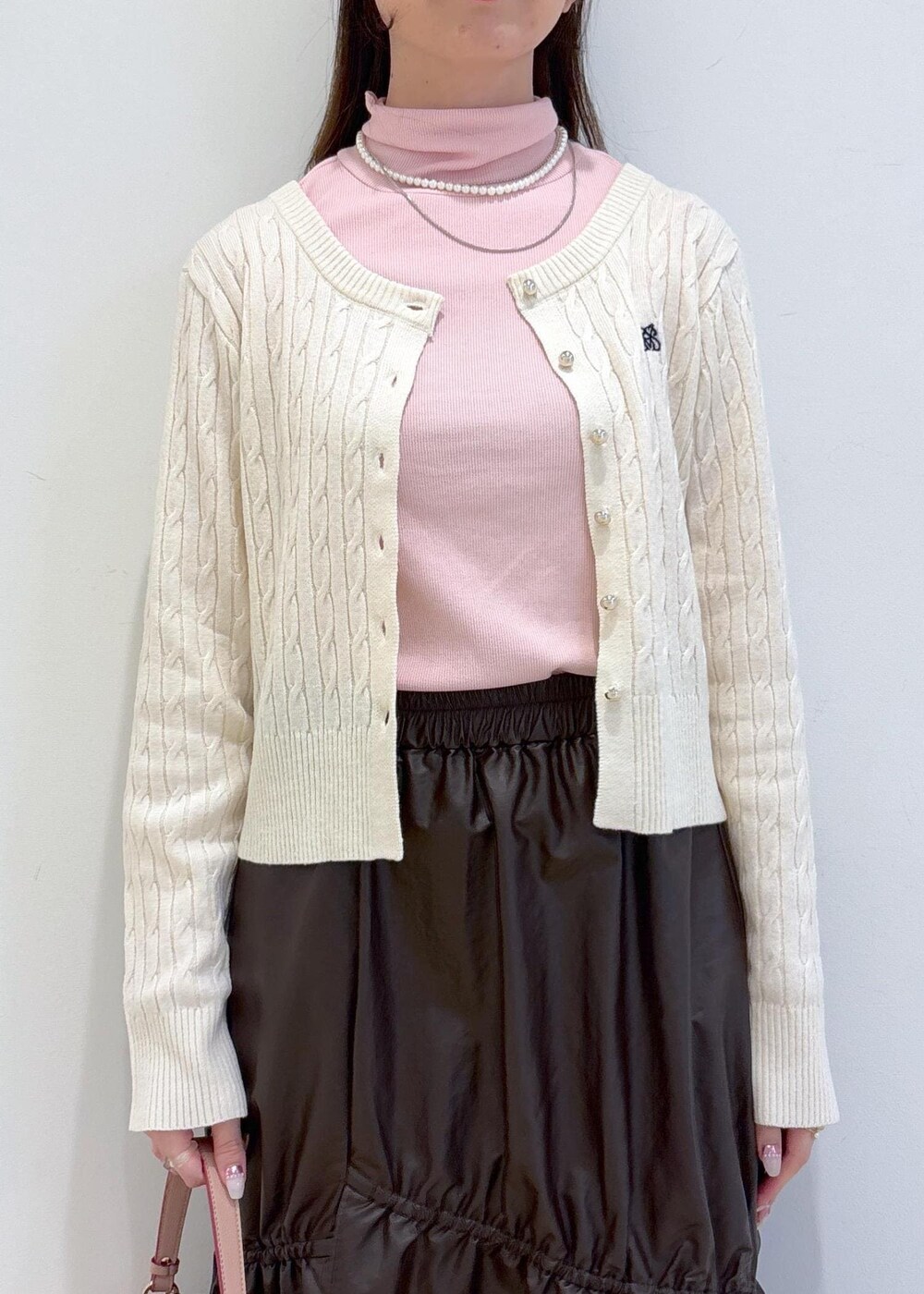 ピンク系のショルダーバッグ、ホワイト系のブーツ、ブラウン系のスカートを着用したレディースの冬コーディネートの7枚目の写真