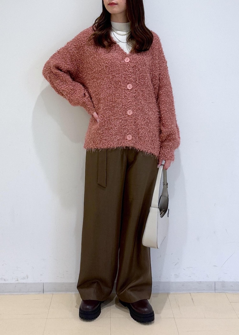 ブラウン系のブーツ、ピンク系のカーディガン/ボレロ、ホワイト系のニット/セーターを着用したレディースの冬コーディネートの3枚目の写真