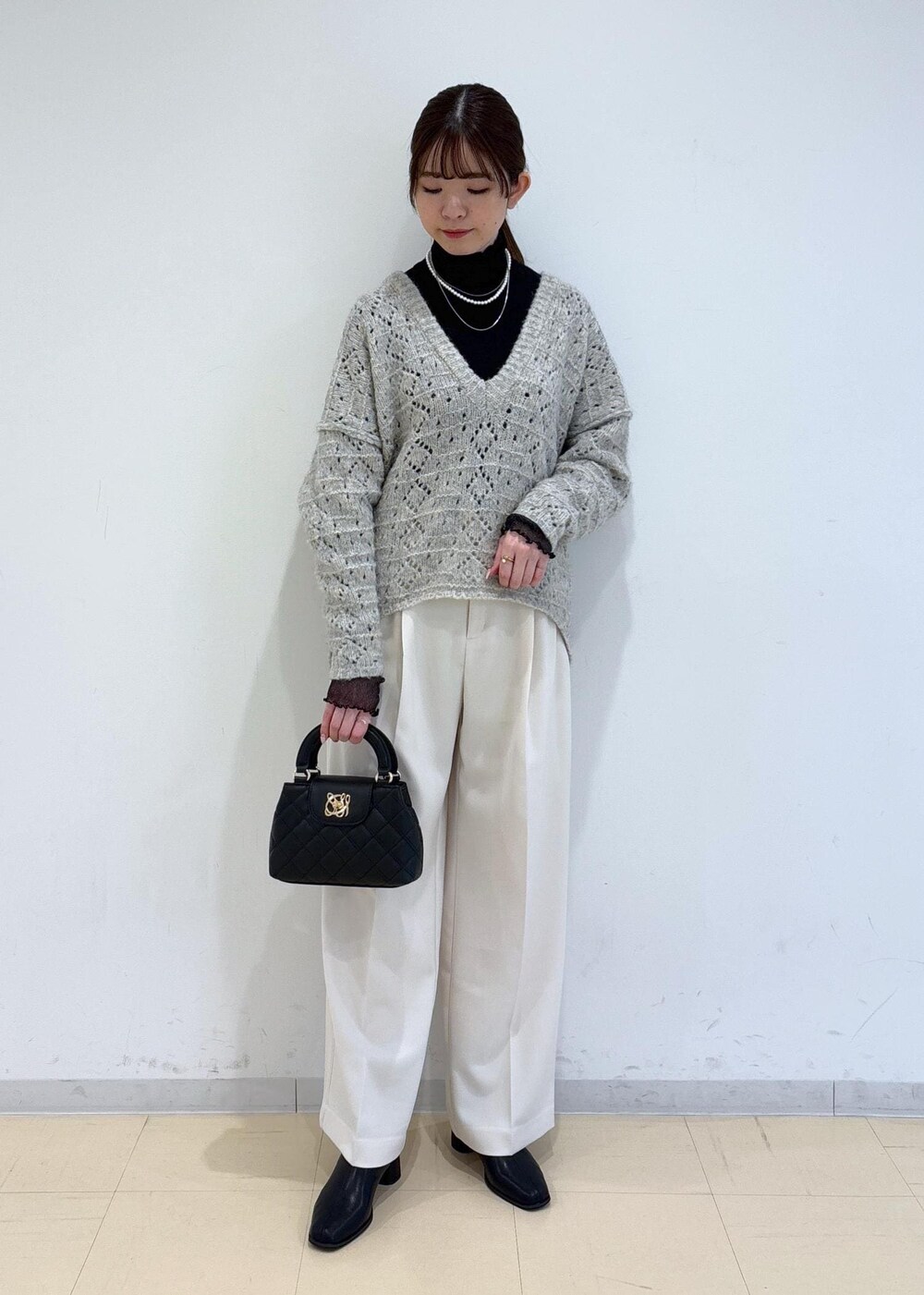 ブラック系のブーツ、ブラック系のTシャツ/カットソー、ベージュ系のニット/セーターを着用したレディースの冬コーディネートの2枚目の写真