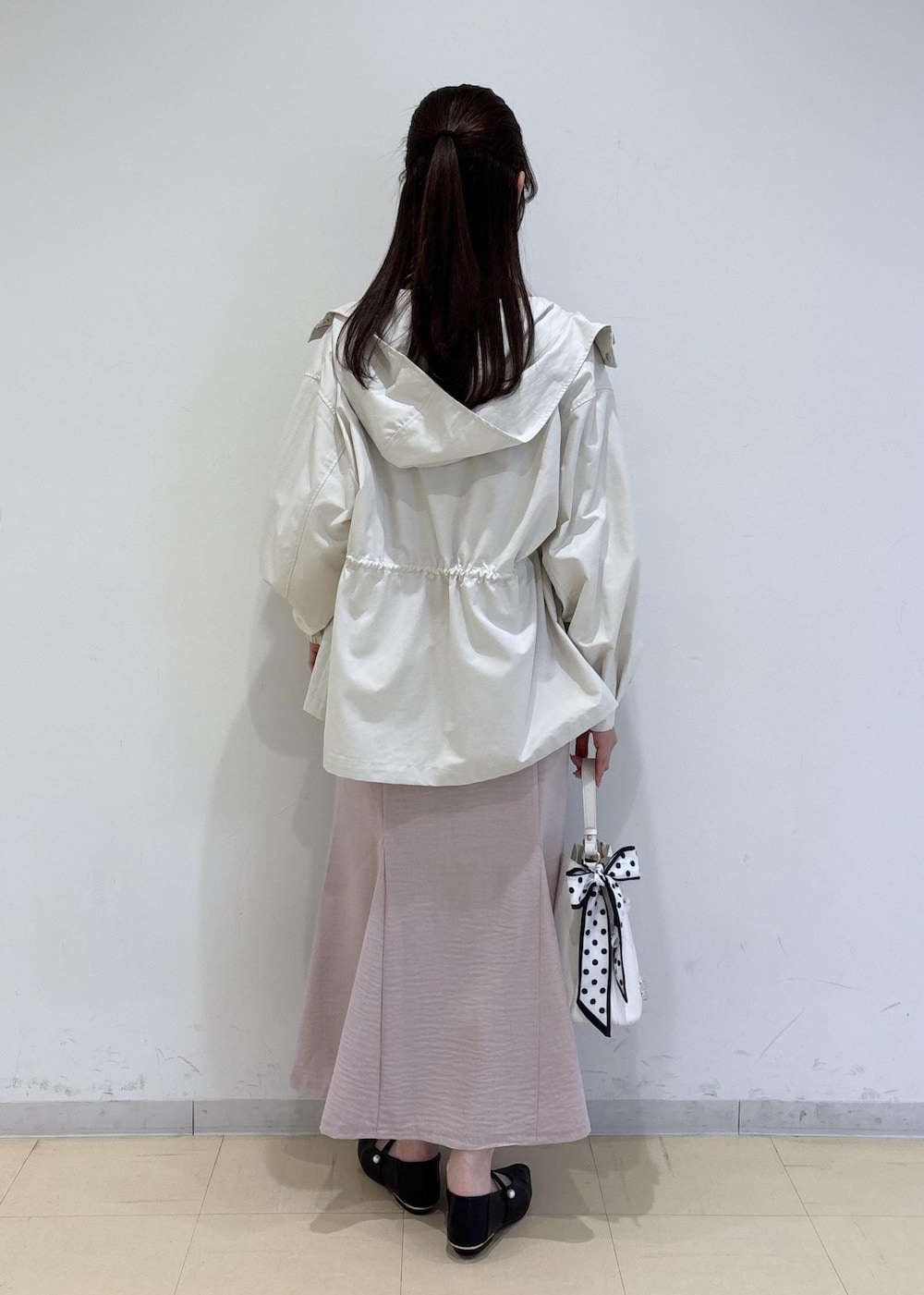 ホワイト系のショルダーバッグ、ブラック系のパンプス、ホワイト系のナイロンジャケットを着用したレディースの春コーディネートの3枚目の写真