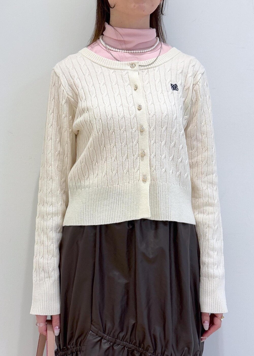 ピンク系のショルダーバッグ、ホワイト系のブーツ、ブラウン系のスカートを着用したレディースの冬コーディネートの6枚目の写真