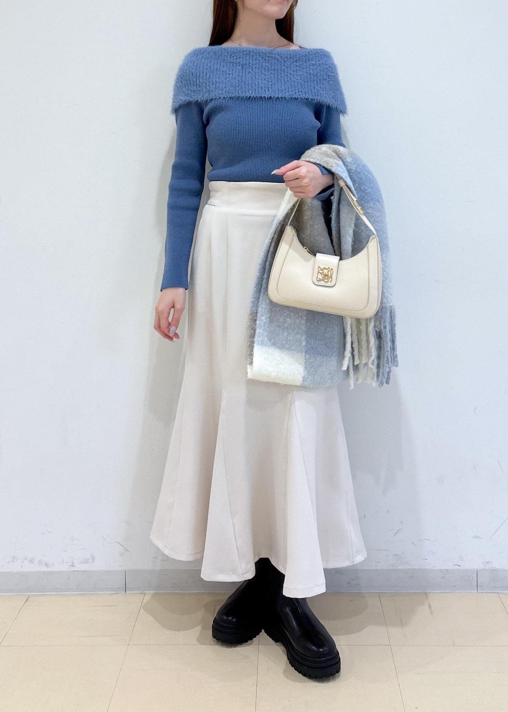 ホワイト系のショルダーバッグ、ブラック系のブーツ、ブルー系のニット/セーターを着用したレディースの秋コーディネートの2枚目の写真