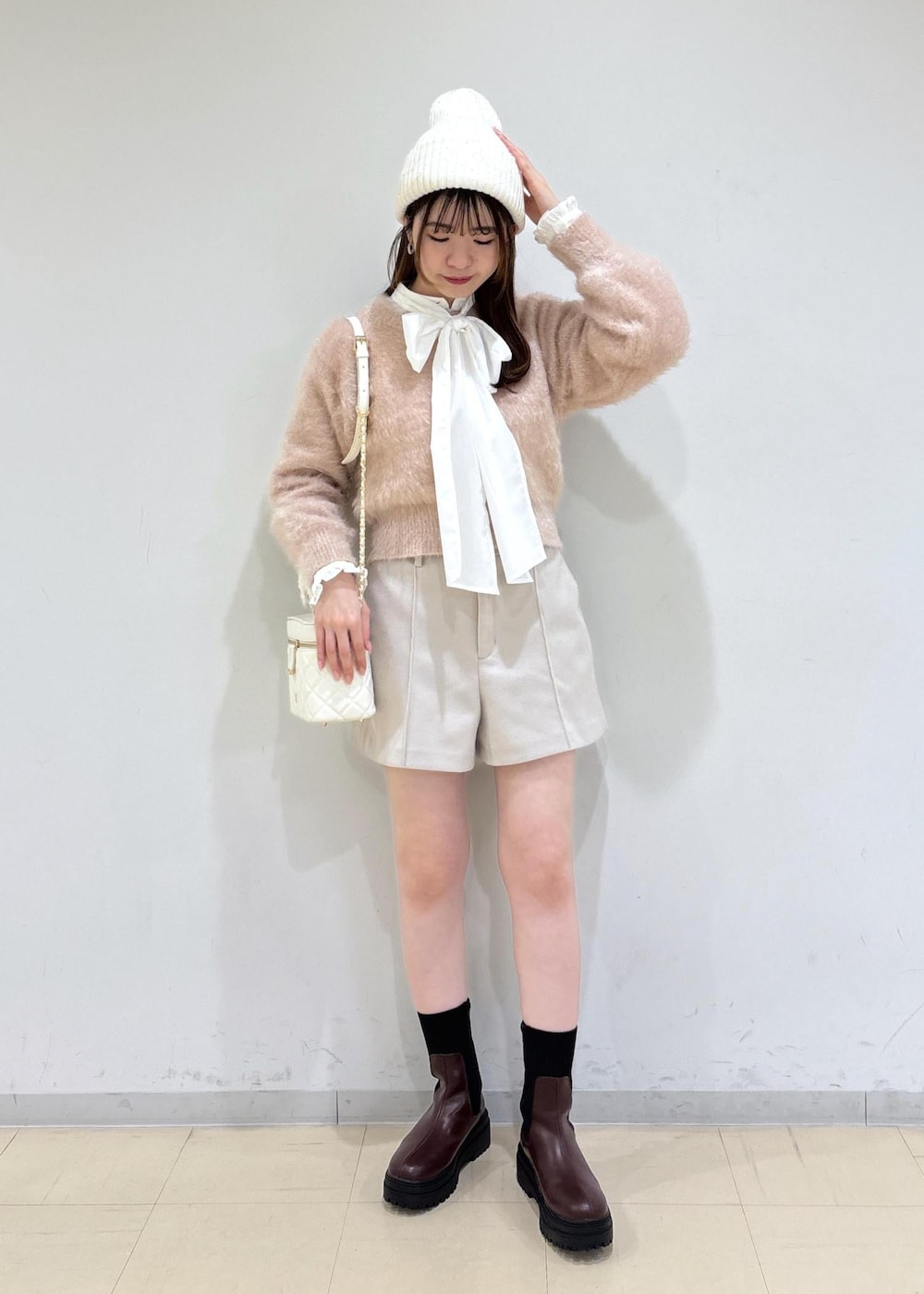 ブラウン系のブーツ、ベージュ系のその他パンツ、ホワイト系のハンドバッグを着用したレディースの冬コーディネートの2枚目の写真