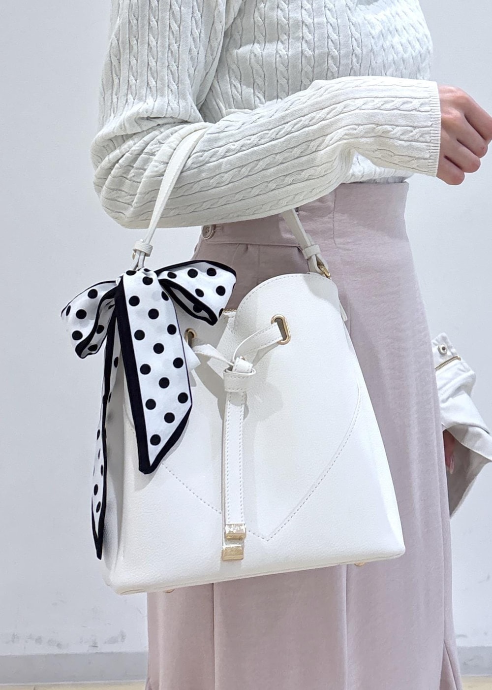 ホワイト系のショルダーバッグ、ブラック系のパンプス、ホワイト系のナイロンジャケットを着用したレディースの春コーディネートの9枚目の写真