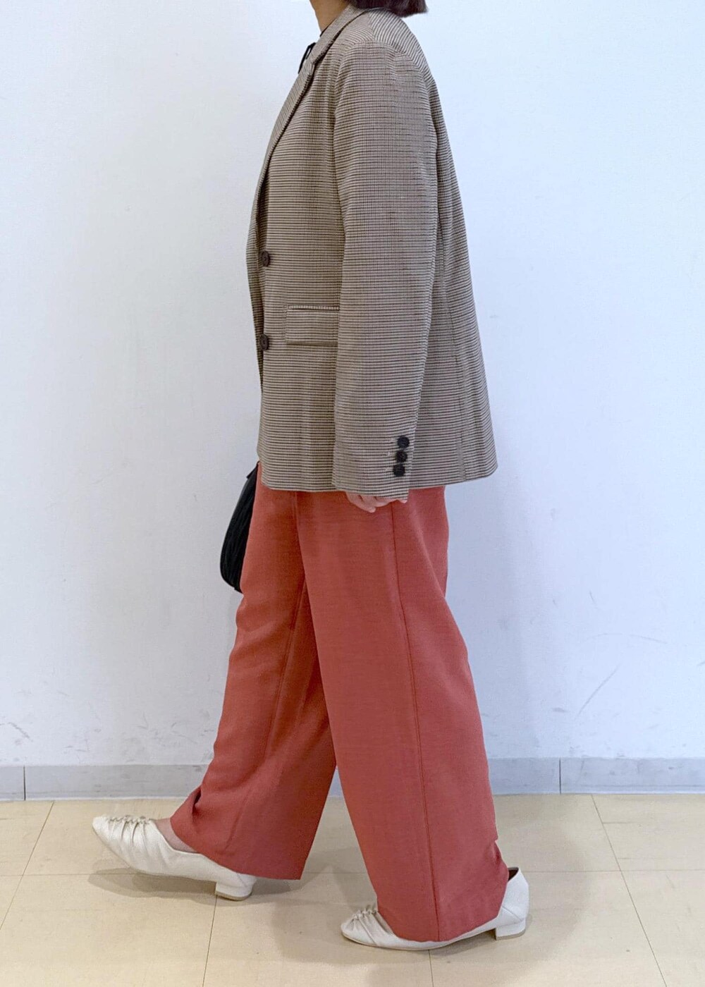 オレンジ系のスラックス、ベージュ系のテーラードジャケット、ホワイト系のTシャツ/カットソーを着用したレディースの秋コーディネートの4枚目の写真