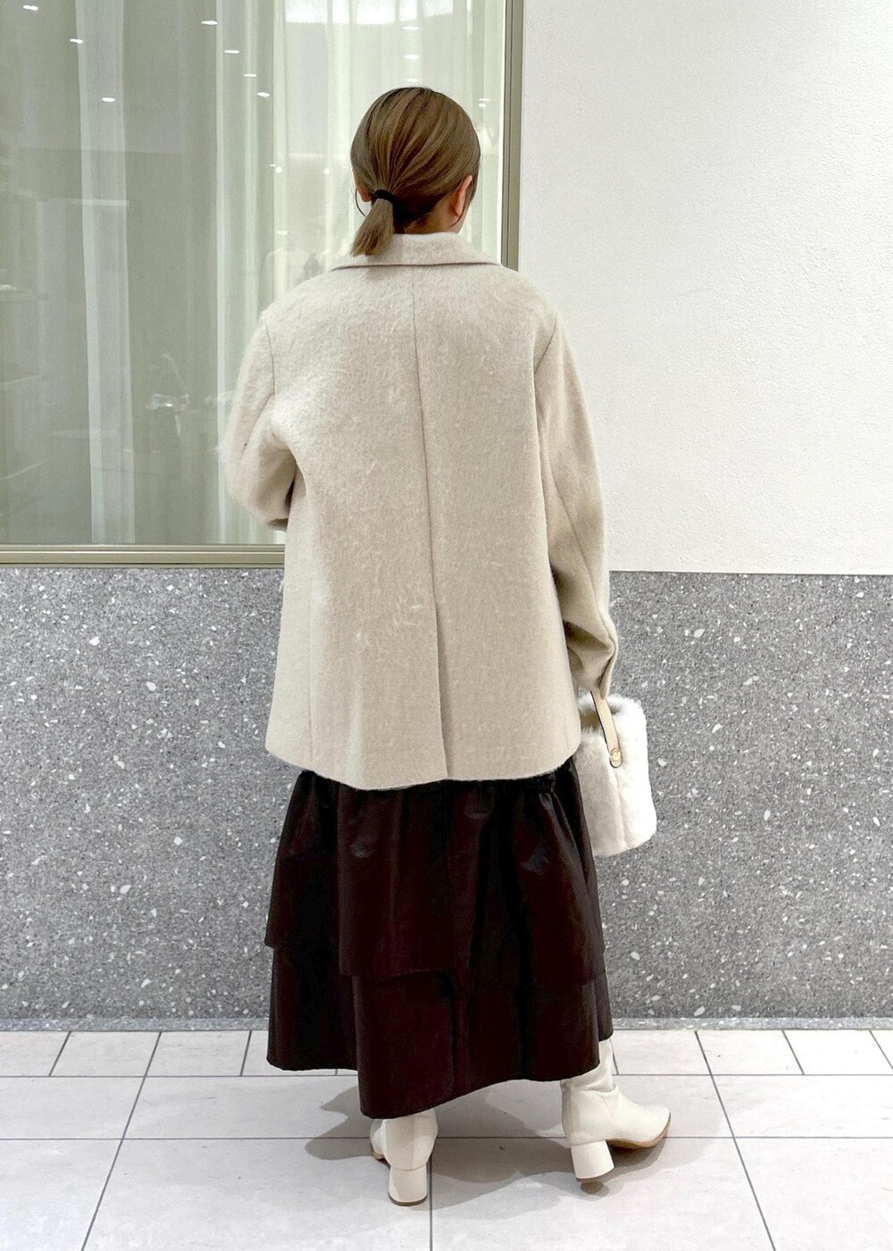 ホワイト系のブーツ、ベージュ系のスカート、ホワイト系のニット/セーターを着用したレディースの秋コーディネートの3枚目の写真