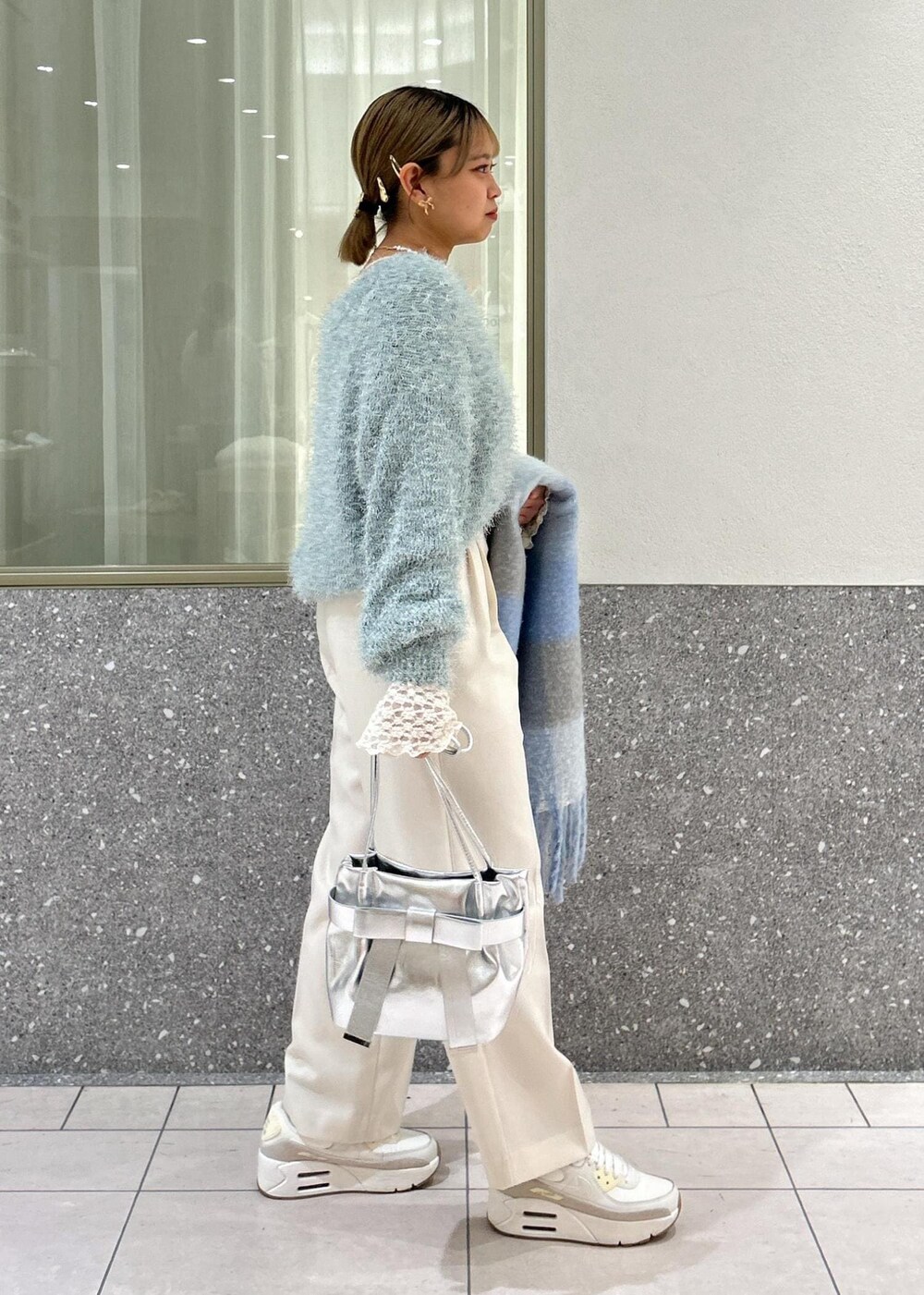 グリーン系のニット/セーター、ホワイト系のTシャツ/カットソー、シルバー系のショルダーバッグを着用したレディースの冬コーディネートの2枚目の写真