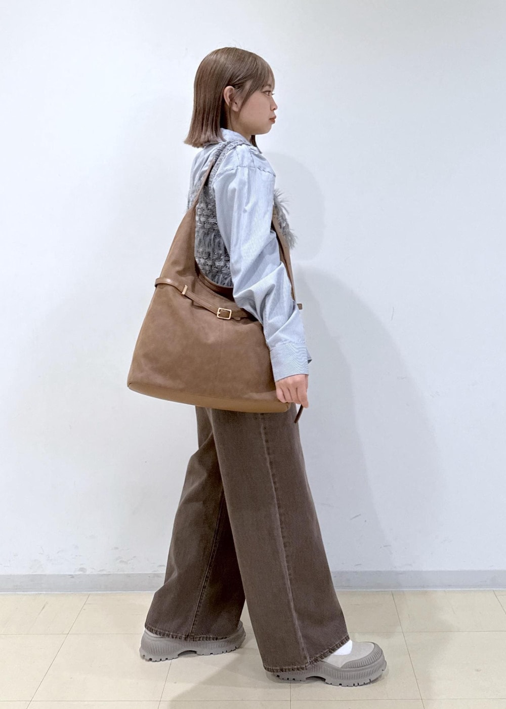 ブラウン系のショルダーバッグ、ブラウン系のデニムパンツ、ブルー系のシャツ/ブラウスを着用したレディースの秋コーディネートの3枚目の写真