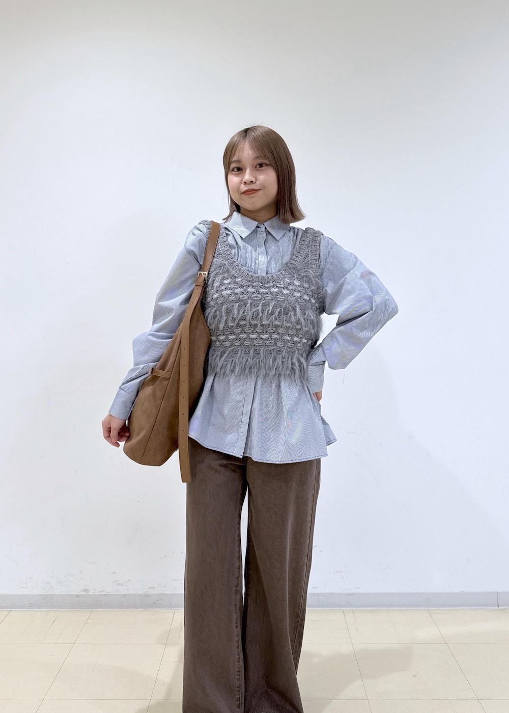 ブラウン系のショルダーバッグ、ブラウン系のデニムパンツ、ブルー系のシャツ/ブラウスを着用したレディースの秋コーディネートの6枚目の写真