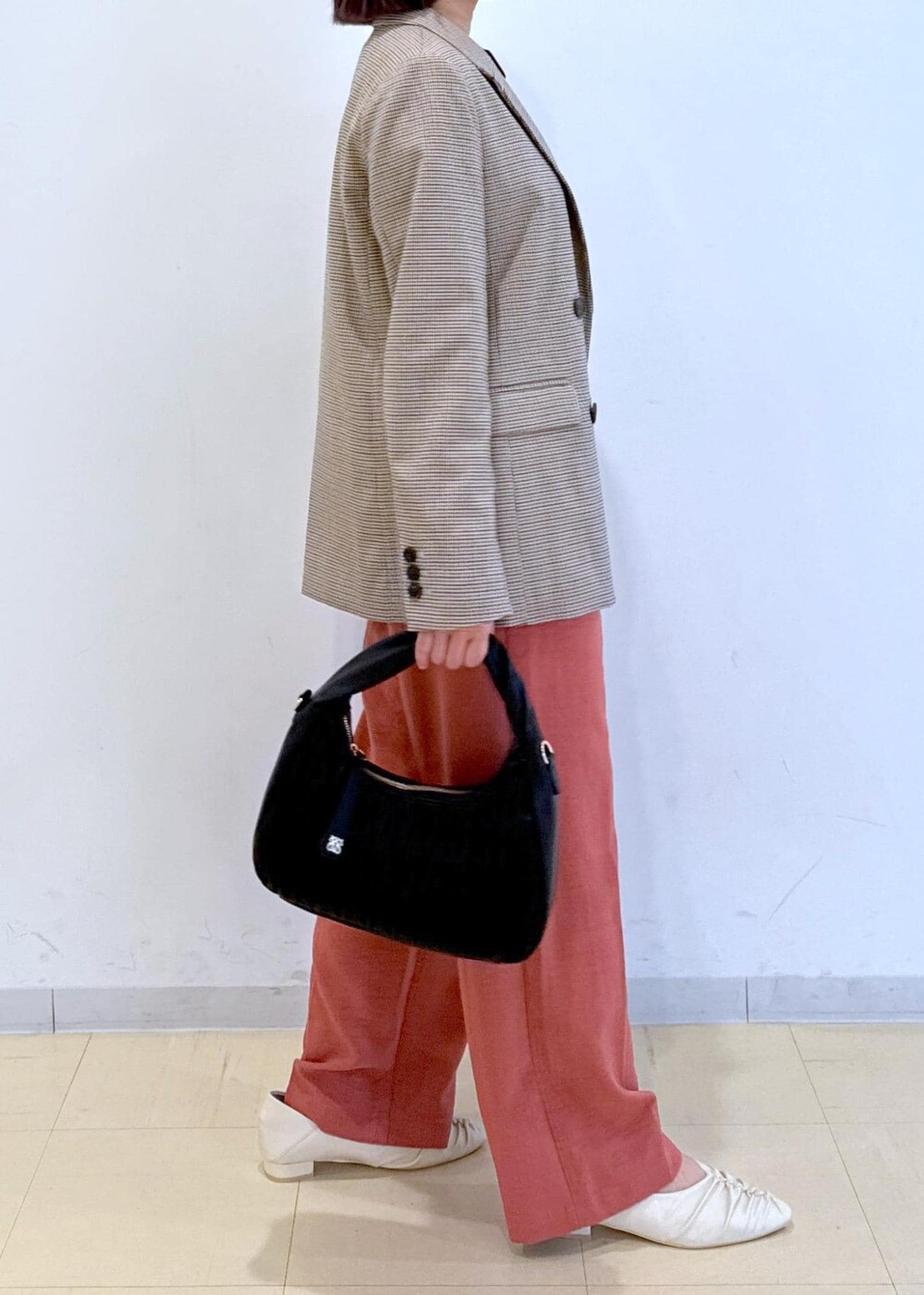 オレンジ系のスラックス、ベージュ系のテーラードジャケット、ホワイト系のTシャツ/カットソーを着用したレディースの秋コーディネートの2枚目の写真