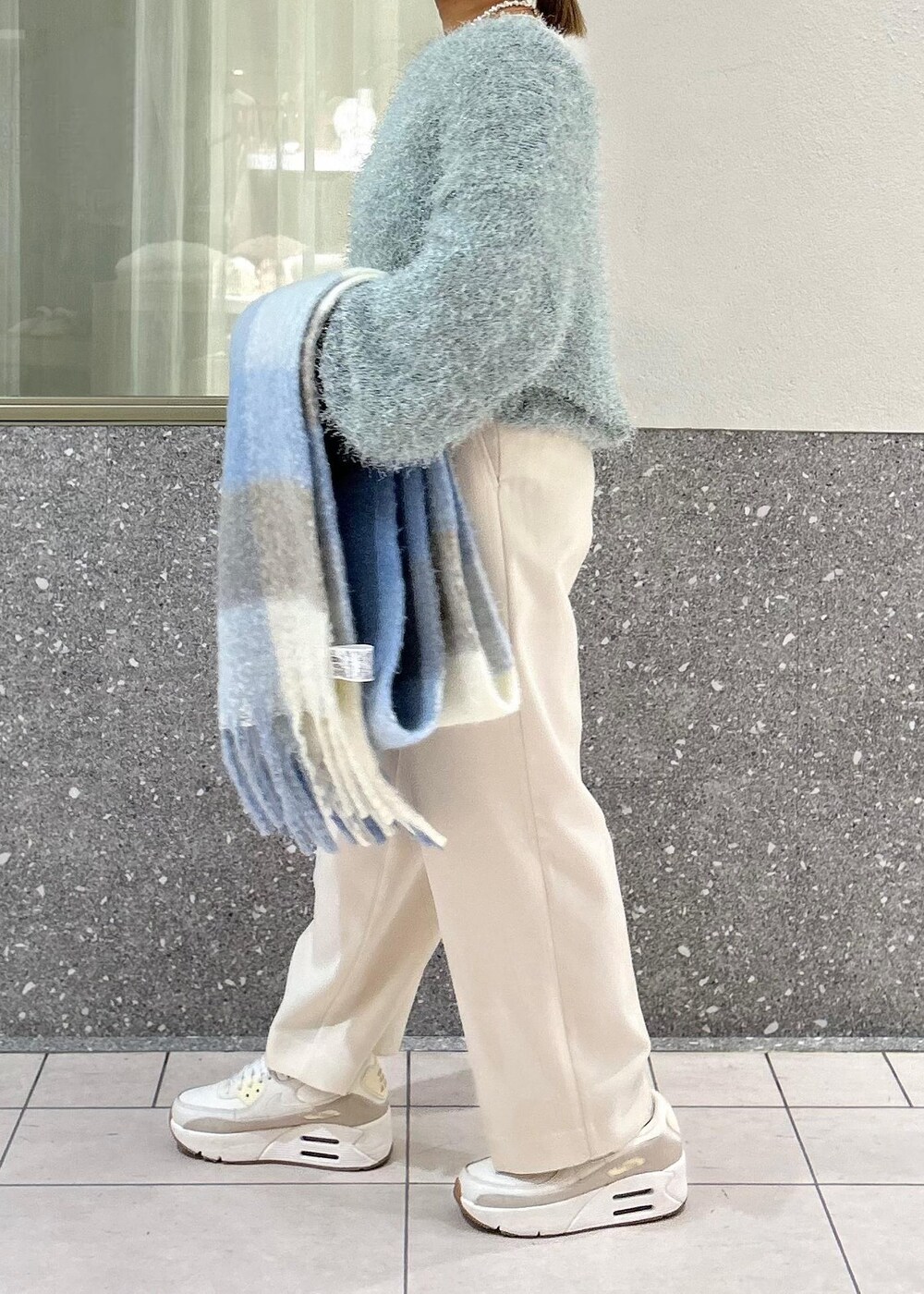グリーン系のニット/セーター、ホワイト系のTシャツ/カットソー、シルバー系のショルダーバッグを着用したレディースの冬コーディネートの4枚目の写真