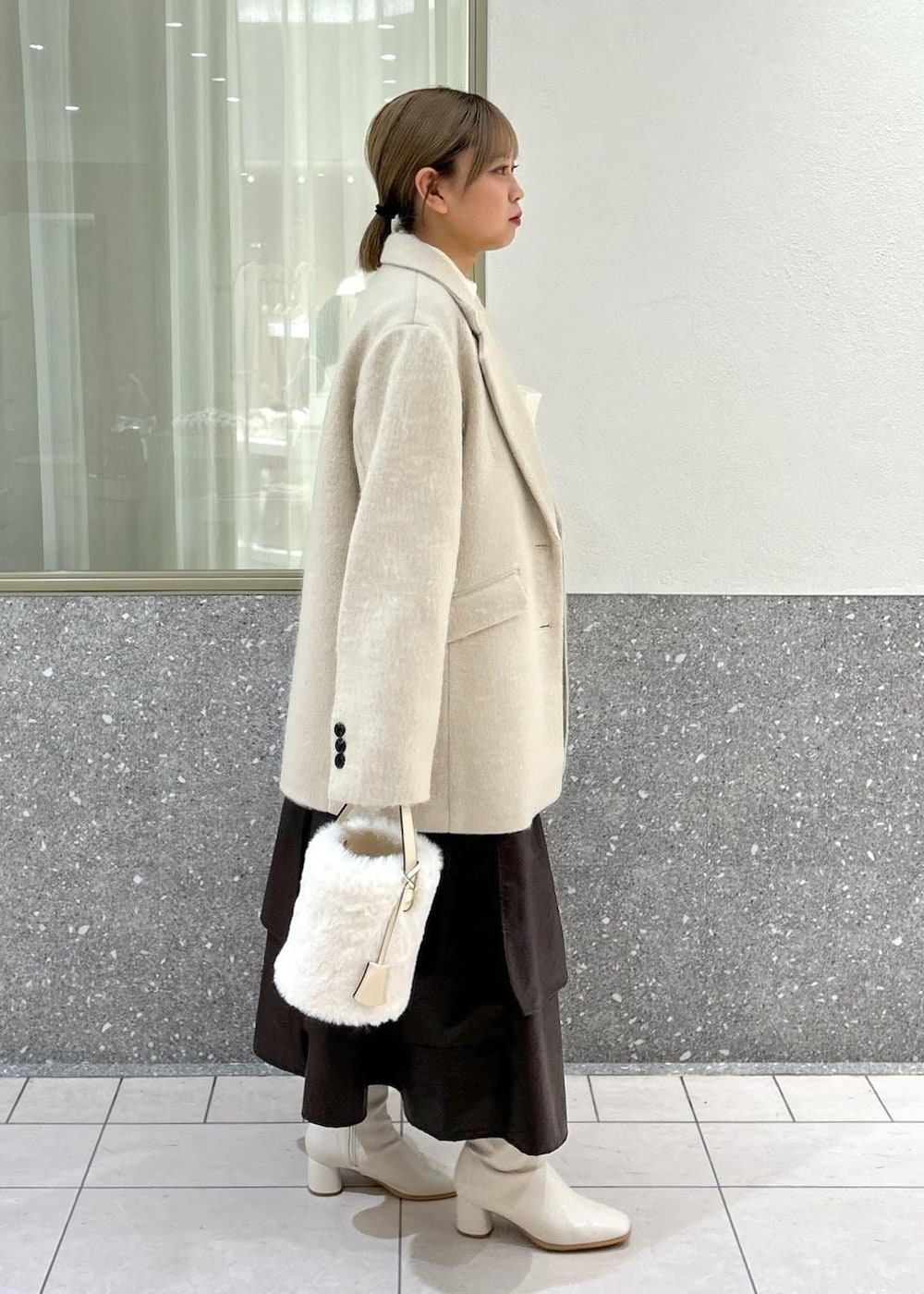 ホワイト系のブーツ、ベージュ系のスカート、ホワイト系のニット/セーターを着用したレディースの秋コーディネートの2枚目の写真