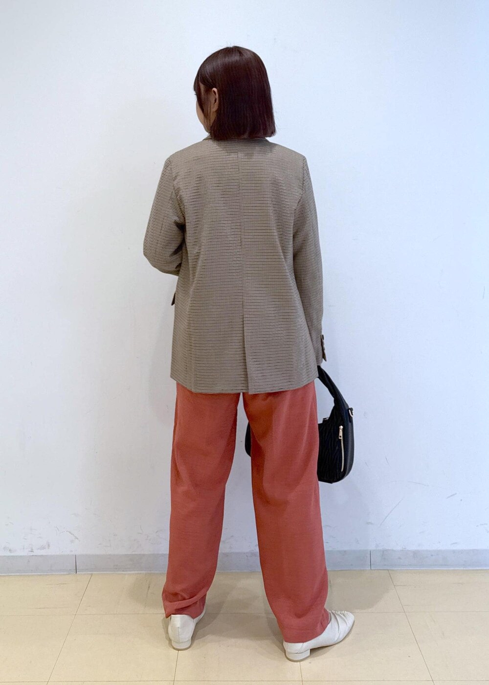 オレンジ系のスラックス、ベージュ系のテーラードジャケット、ホワイト系のTシャツ/カットソーを着用したレディースの秋コーディネートの3枚目の写真