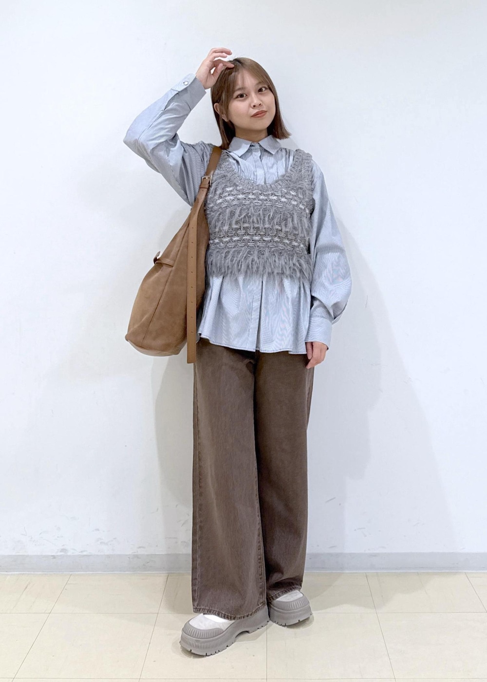 ブラウン系のショルダーバッグ、ブラウン系のデニムパンツ、ブルー系のシャツ/ブラウスを着用したレディースの秋コーディネートの2枚目の写真