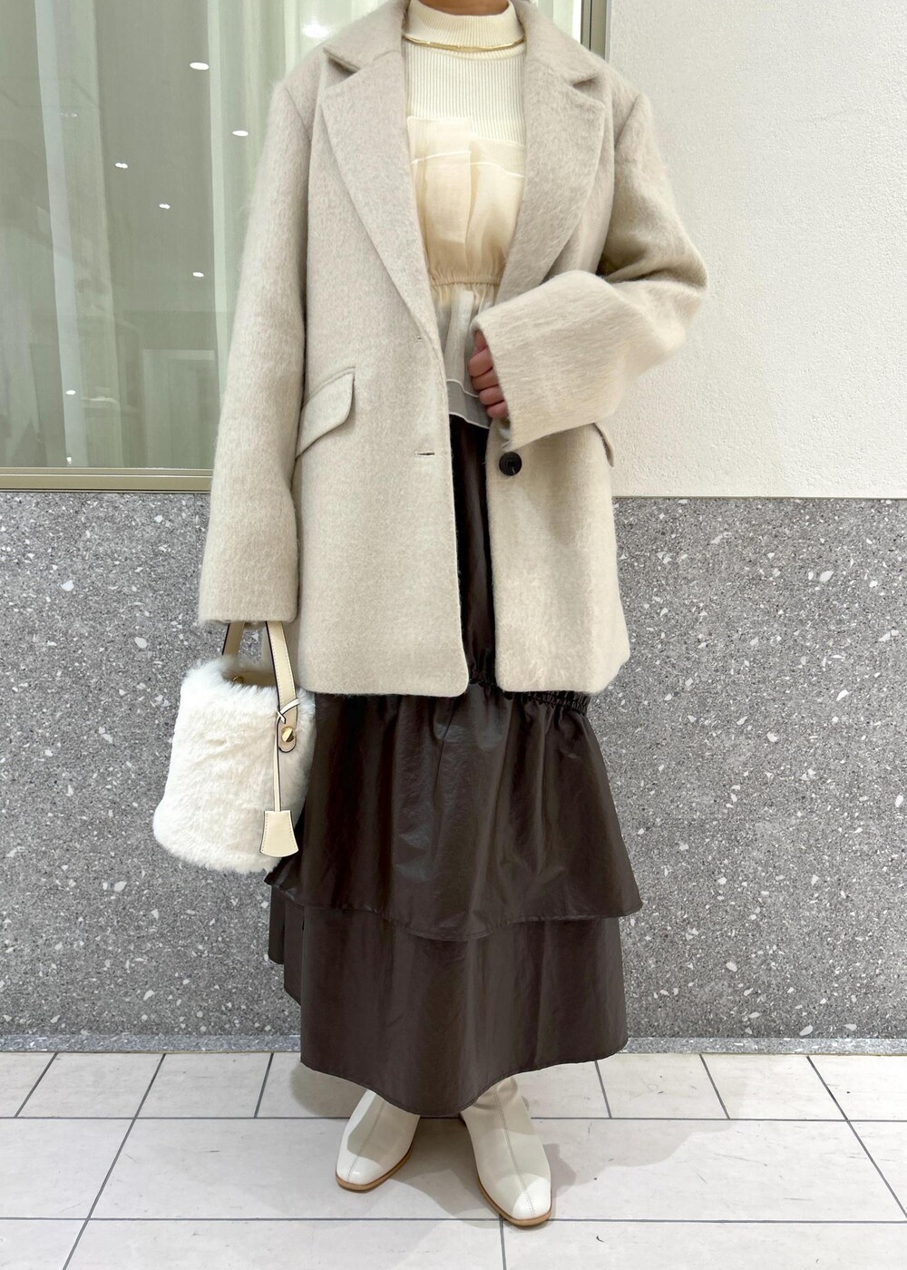 ホワイト系のブーツ、ベージュ系のスカート、ホワイト系のニット/セーターを着用したレディースの秋コーディネートの10枚目の写真