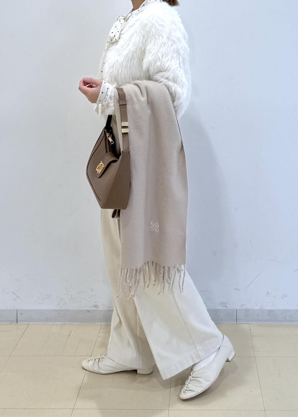 ブラウン系のショルダーバッグ、ホワイト系のパンプス、ホワイト系のカーディガン/ボレロを着用したレディースの冬コーディネートの2枚目の写真