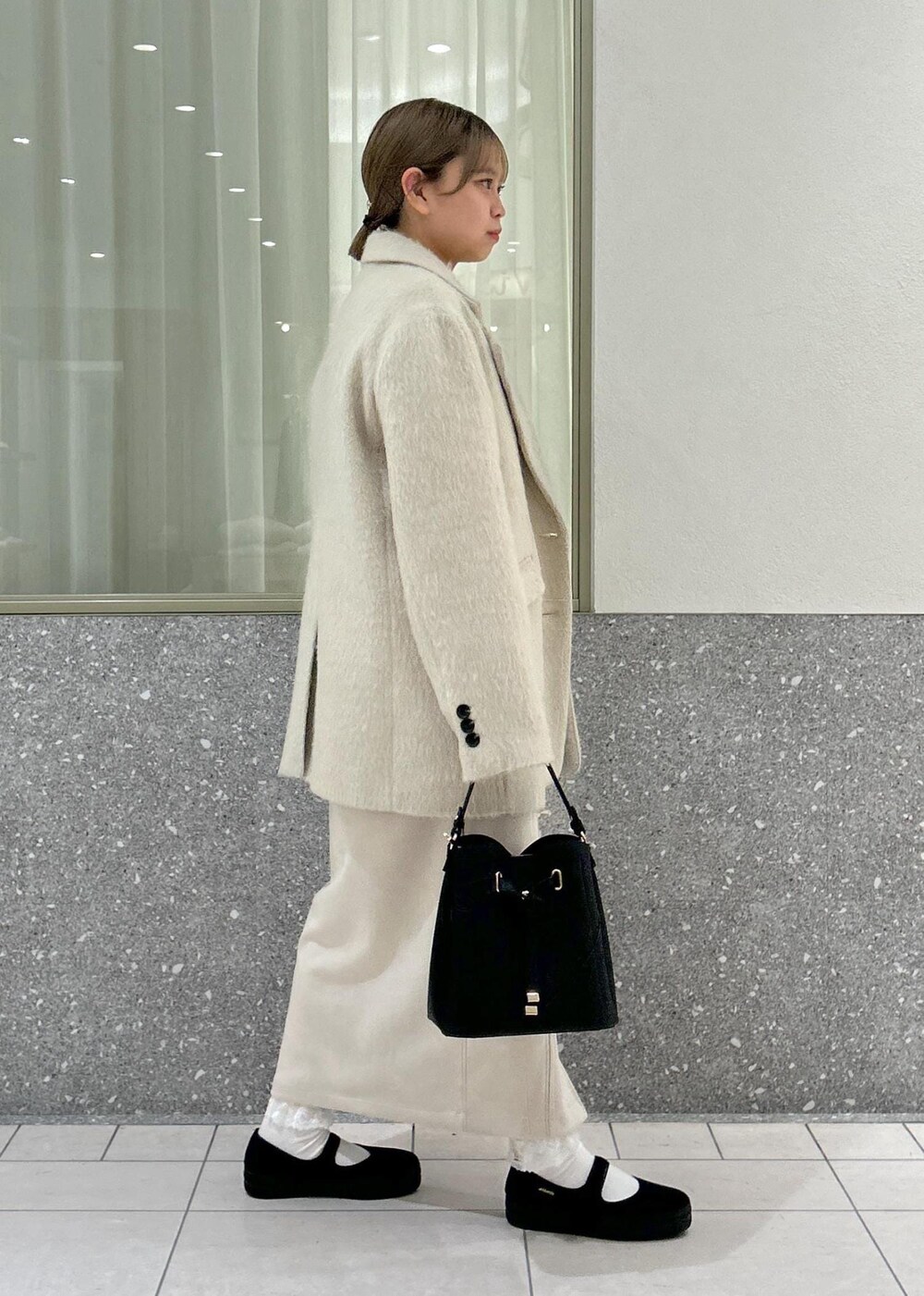 ベージュ系のスカート、グレー系のニット/セーター、ブラウン系のその他アウターを着用したレディースの冬コーディネートの4枚目の写真