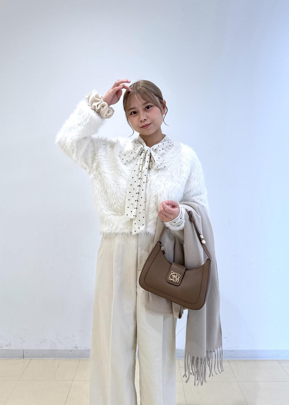 ブラウン系のショルダーバッグ、ホワイト系のパンプス、ホワイト系のカーディガン/ボレロを着用したレディースの冬コーディネートの5枚目の写真