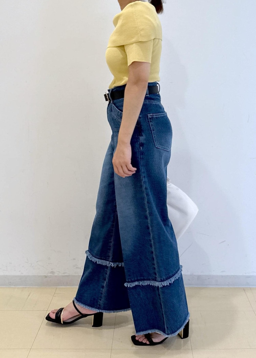 ブラック系のサンダル、ブルー系のデニムパンツ、イエロー系のニット/セーターを着用したレディースの夏コーディネートの3枚目の写真