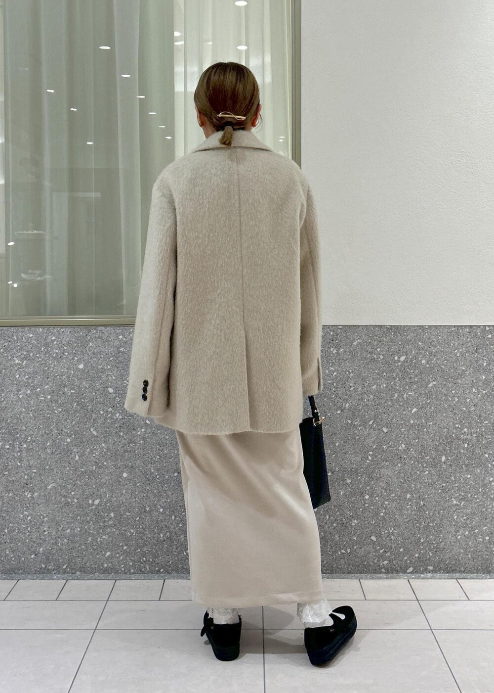 ベージュ系のスカート、グレー系のニット/セーター、ブラウン系のその他アウターを着用したレディースの冬コーディネートの3枚目の写真