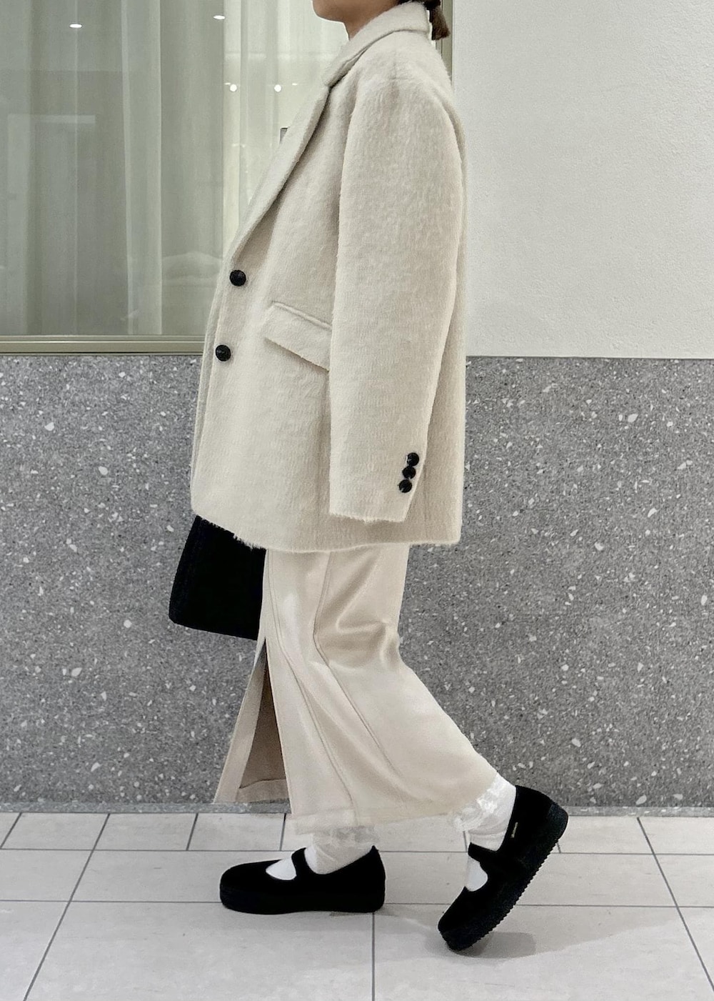 ベージュ系のスカート、グレー系のニット/セーター、ブラウン系のその他アウターを着用したレディースの冬コーディネートの2枚目の写真