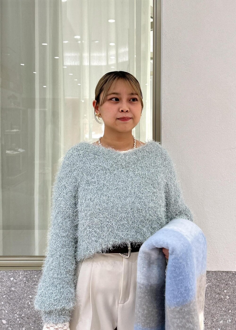 グリーン系のニット/セーター、ホワイト系のTシャツ/カットソー、シルバー系のショルダーバッグを着用したレディースの冬コーディネートの9枚目の写真