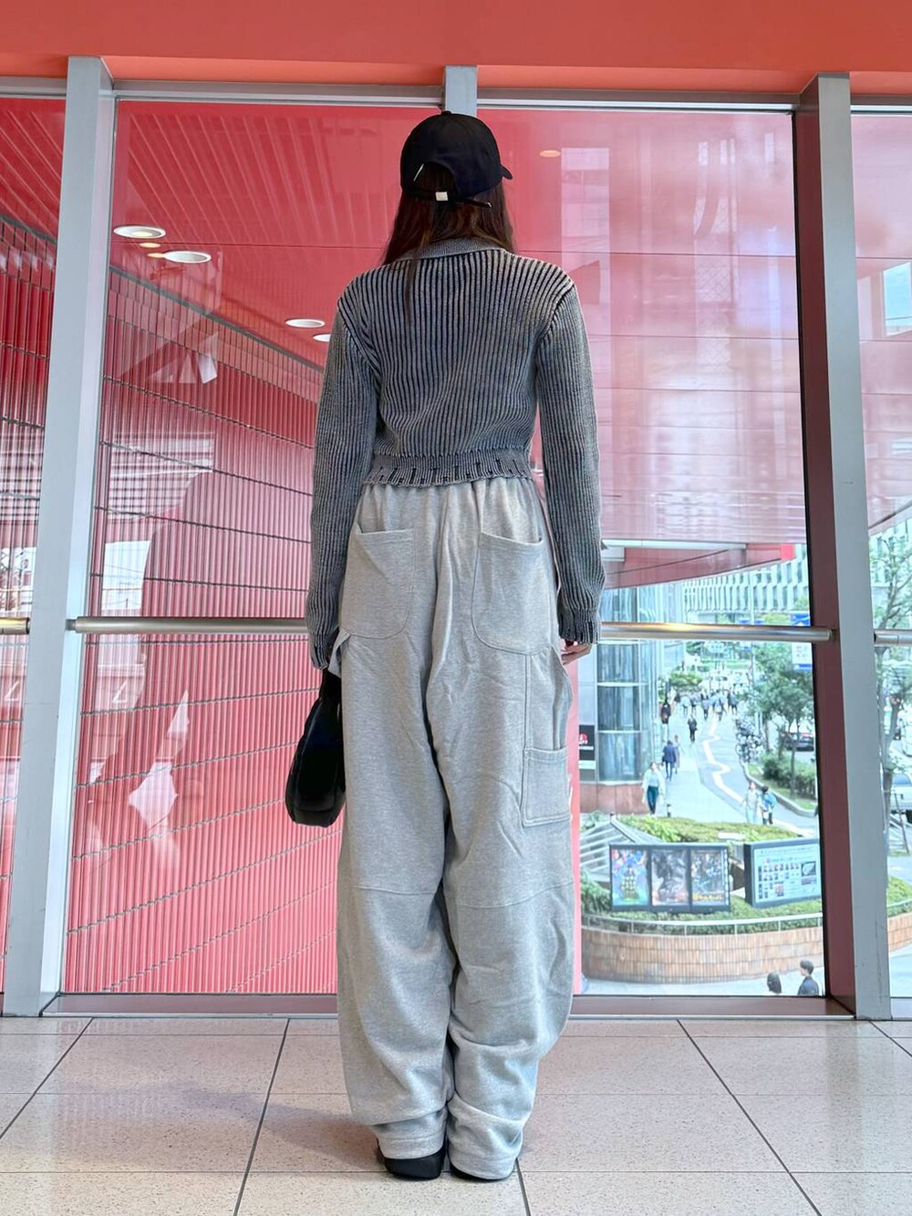 ブラック系のハンドバッグ、ブラック系のニット/セーター、グレー系のスウェットパンツを着用したレディースの秋コーディネートの3枚目の写真