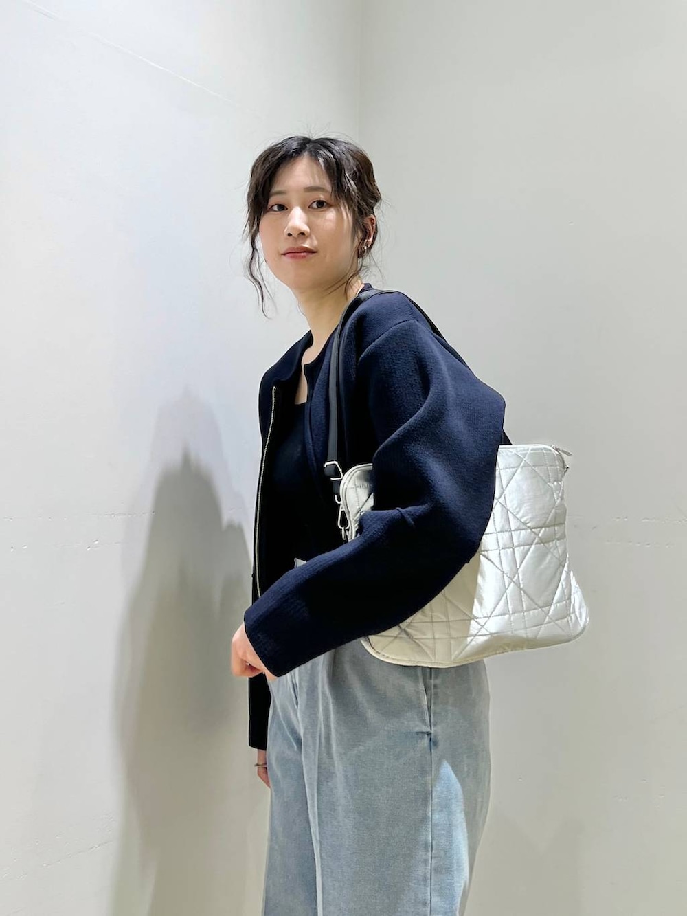 ブルー系のデニムパンツ、ブラック系のニット/セーター、ホワイト系のトートバッグを着用したレディースの冬コーディネートの3枚目の写真