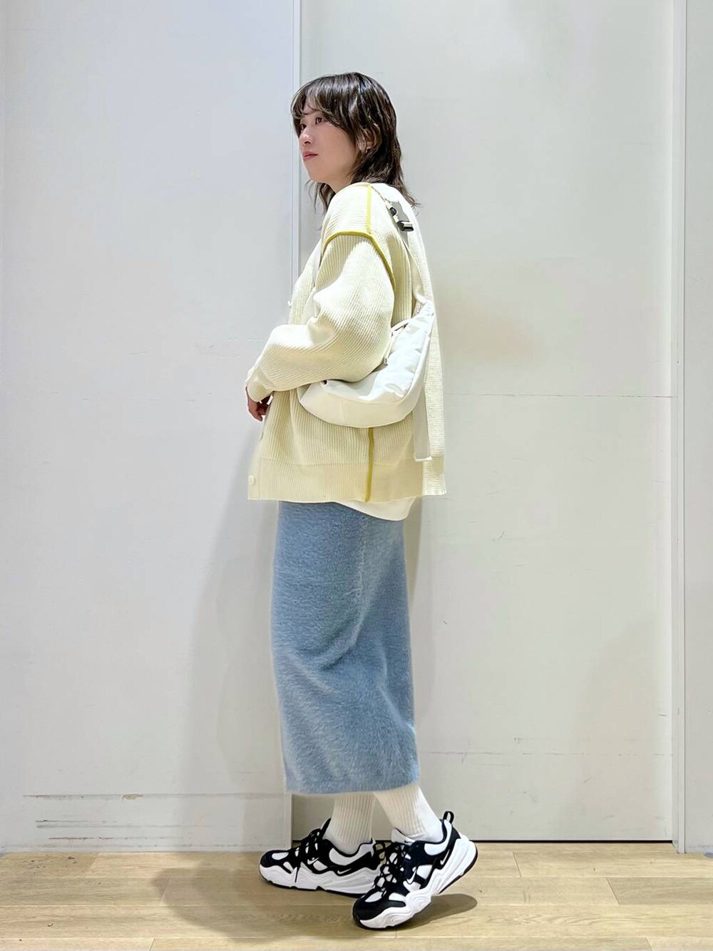 ホワイト系のショルダーバッグ、ブルー系のスカート、ホワイト系のカーディガン/ボレロを着用したレディースの冬コーディネートの2枚目の写真