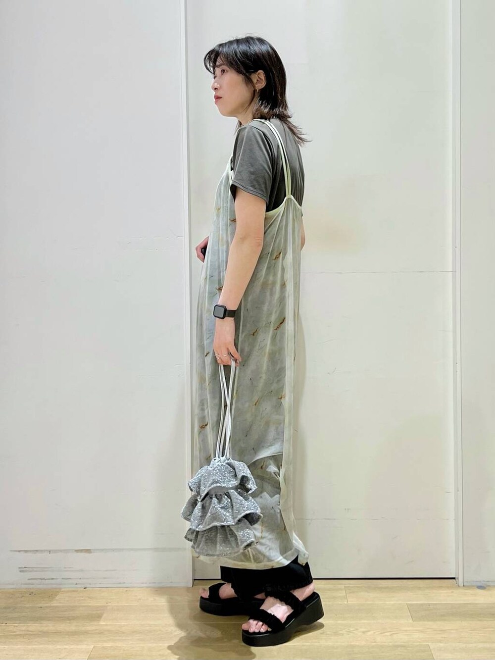 シルバー系のショルダーバッグ、ブラック系のデニムパンツ、グレー系のTシャツ/カットソーを着用したレディースの春コーディネートの2枚目の写真