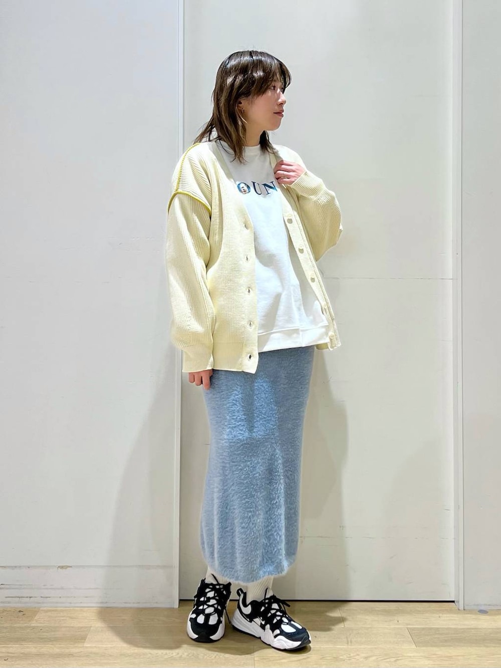 ホワイト系のショルダーバッグ、ブルー系のスカート、ホワイト系のカーディガン/ボレロを着用したレディースの冬コーディネートの6枚目の写真