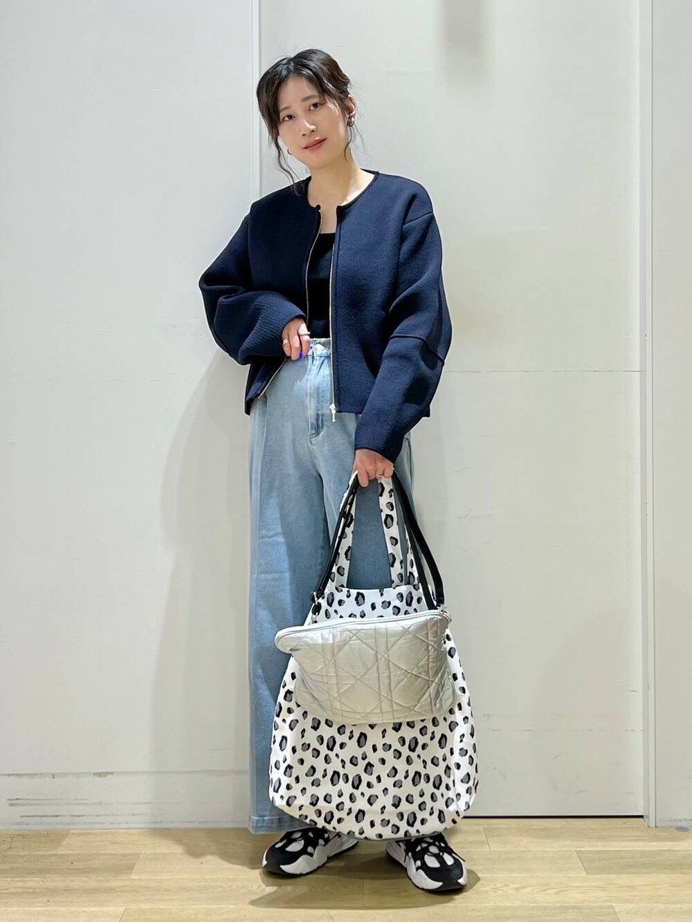 ブルー系のデニムパンツ、ブラック系のニット/セーター、ホワイト系のトートバッグを着用したレディースの冬コーディネートの2枚目の写真