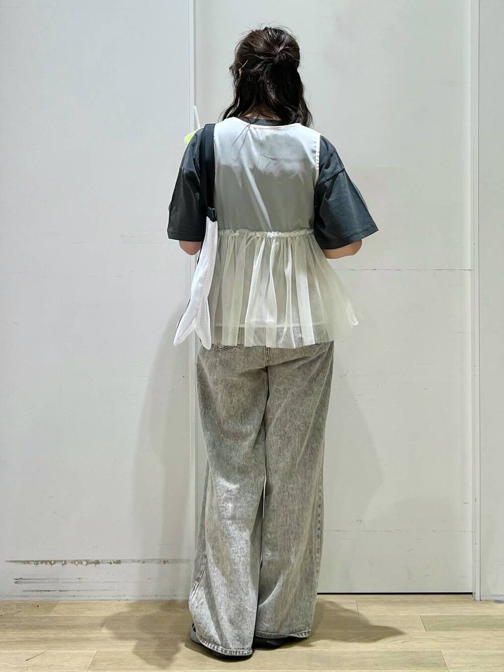 グレー系のデニムパンツ、ベージュ系のベスト、グレー系のTシャツ/カットソーを着用したレディースの春コーディネートの3枚目の写真